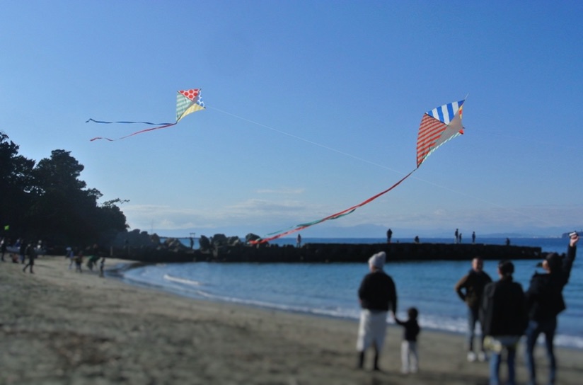 森戸海岸では子供たちが凧揚げをしている。ダイヤ型の凧が２枚上がっている。