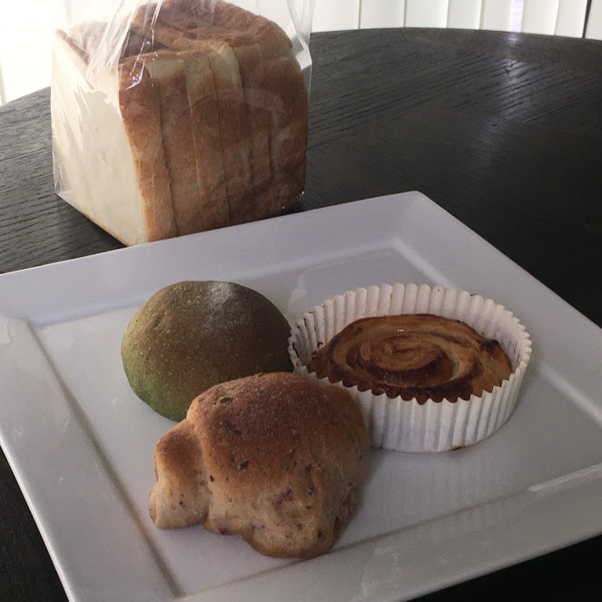 バターロール、緑の丸いパン、渦巻きのパンが白いお皿に並ぶ。場所はThe Canvas Hayama Park
