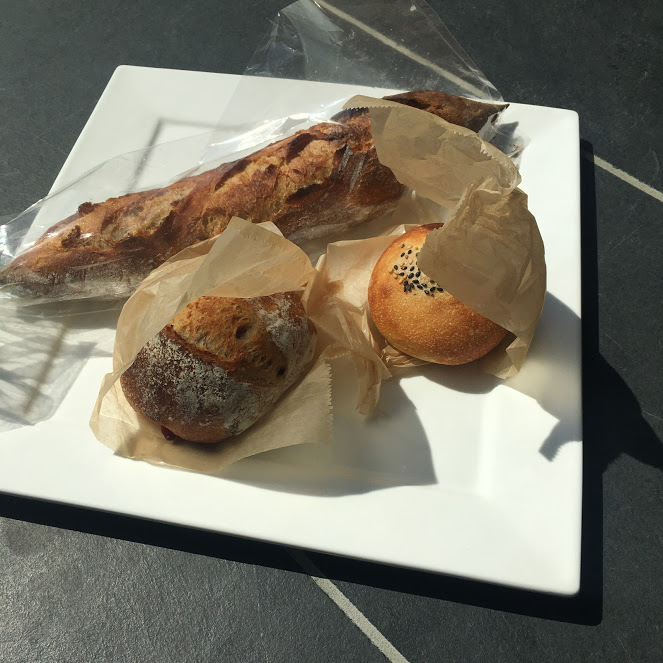 conayaのパン。バケット、アンパン、カンパーニュが白いお皿に並ぶ。場所はThe Canvas Hayama Park